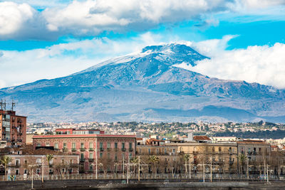 Scenic view of town by mountains against sky