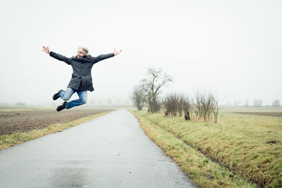 Man jumping on road against clear sky