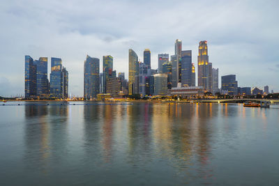 City at waterfront against cloudy sky