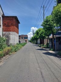 Road by buildings against sky