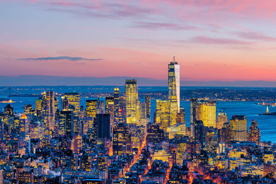 Illuminated buildings in city against sky during sunset