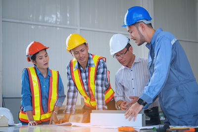 Architect explaining coworkers over blueprint at table