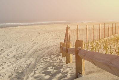 Wooden posts on sand at beach against sky