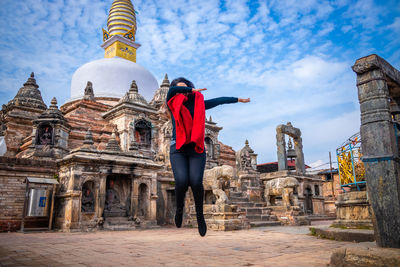 Rear view of man standing outside temple against buildings