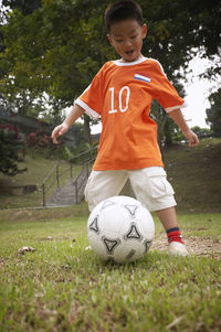 Full length of boy playing soccer on field at park