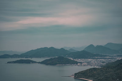 Scenic view of sea by mountains against sky