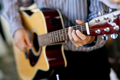 Midsection of man playing guitar