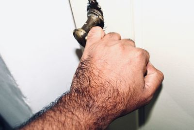 Close-up of man holding hands against wall