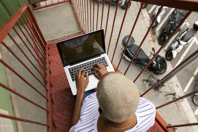 Short-haired woman sitting on outdoor stairs using laptop