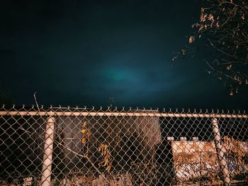 Close-up of chainlink fence against sky at night