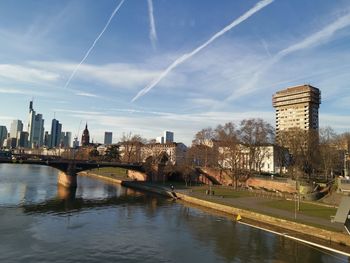 Bridge over river by buildings against sky in city