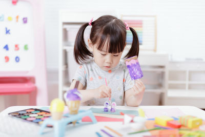 Young girl decorating hand made craft for homeschooling