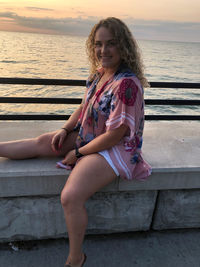 Portrait of woman sitting on railing against sea