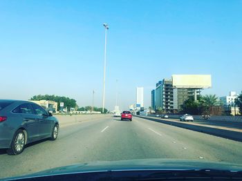 Cars on street against clear blue sky