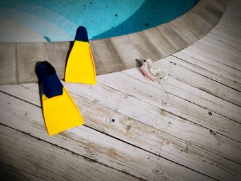 High angle view of yellow flippers on hardwood floor by pool