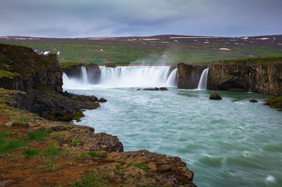 Scenic view of waterfall against sky