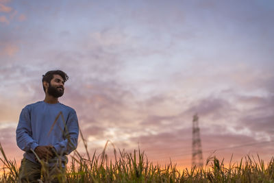 Man standing on field against sky during sunset