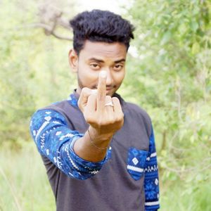 Portrait of young man showing middle finger while standing against plants