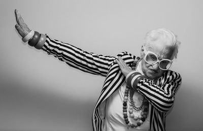 Portrait of woman holding eyeglasses against white background