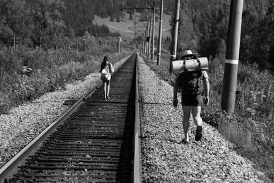 Full length of people hiking on railroad tracks