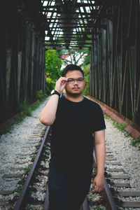 Portrait of young man standing on railroad tracks