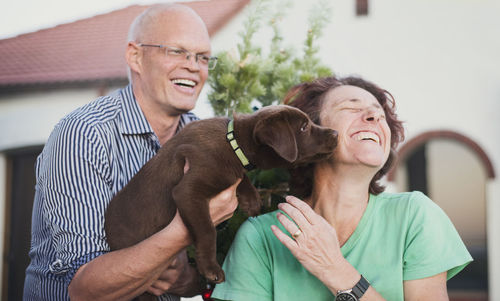 Happy mature couple playing with dog in yard