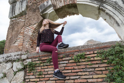 Low angle view of woman sitting on wall