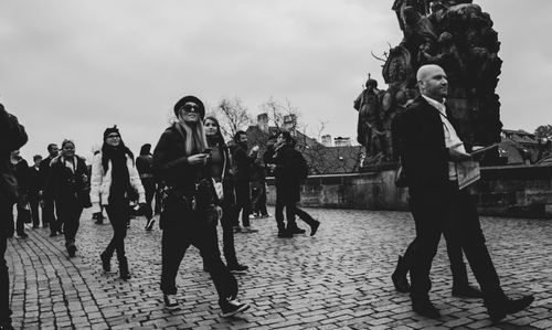 People walking on street in city against sky