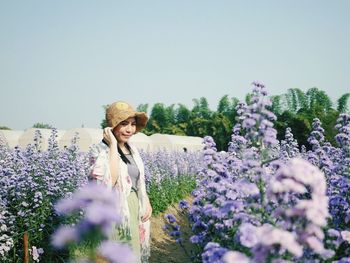 Young woman standing on lavender amidst flowering plants against clear sky