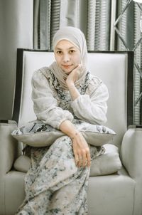 Portrait of young woman sitting on sofa at home