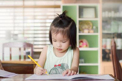 Cute girl studying while sitting at table