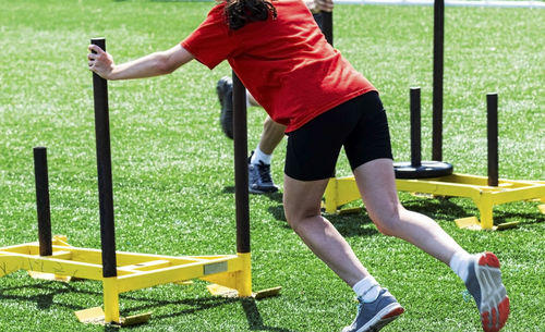 Low section of woman exercising with sled on turf ground