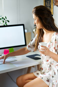 Woman using computer while sitting on table