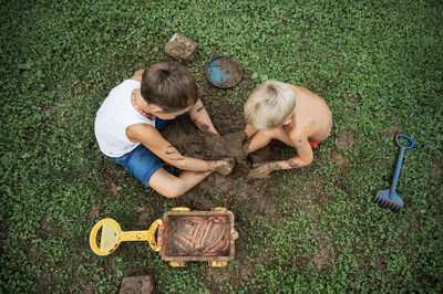 High angle view of siblings digging on land in yard