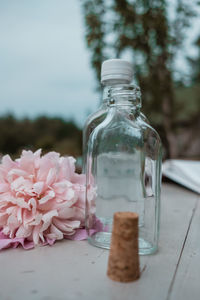 Close-up of glass with pink flowers in jar on table