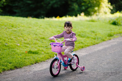 Full length of girl riding bicycle on grass