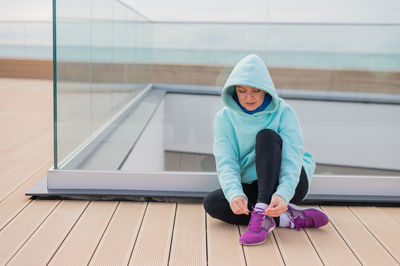 Portrait of young woman sitting on window