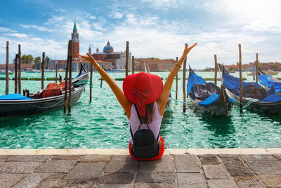 Rear view of woman with arms raised sitting at grand canal