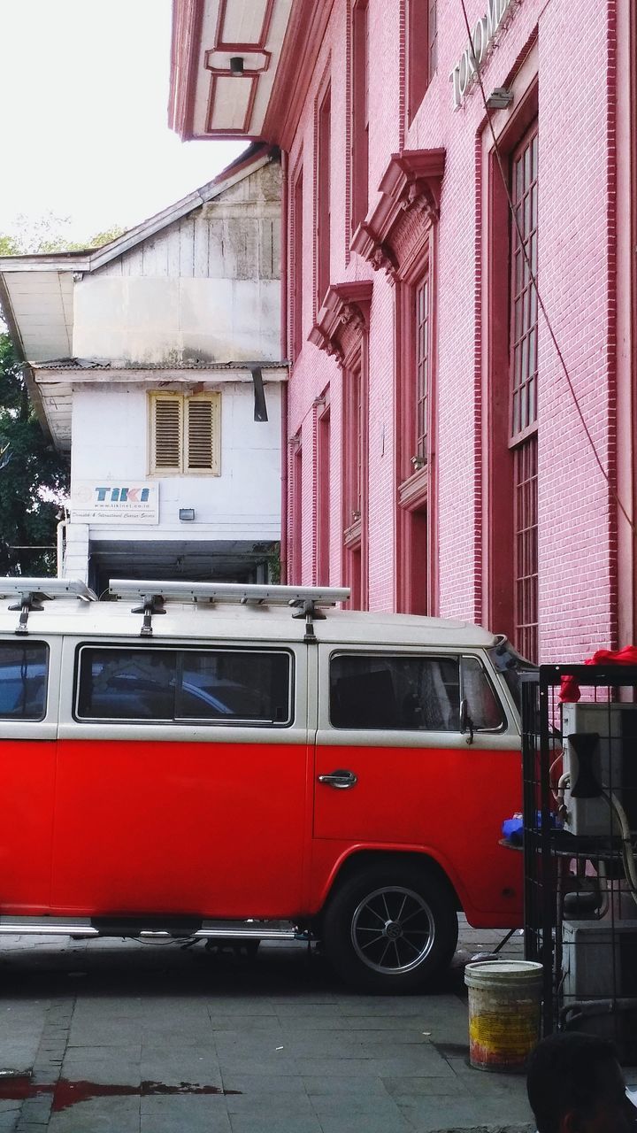 RED CAR ON STREET AGAINST BUILDINGS IN CITY