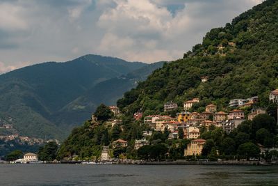 Scenic view of townscape by mountains against sky