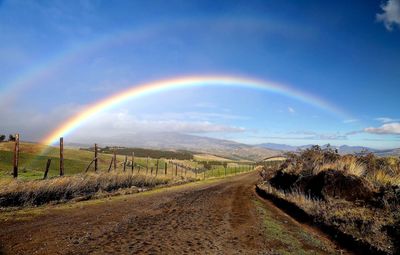 Scenic view of rainbow over road against sky