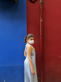 Portrait of woman standing against door