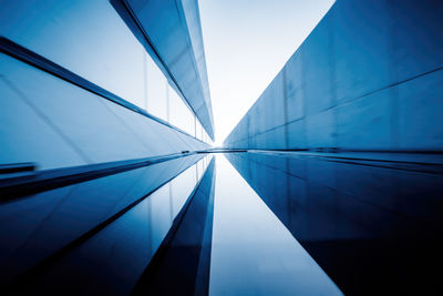 Low angle view of glass building against clear blue sky