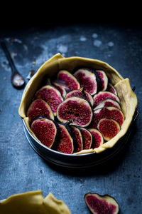 From above baking pan with raw dough and slices of figs placed on dark gray table