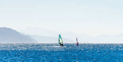 People in sea against clear sky