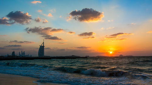 Scenic view of burj al arab and sea against sky during sunset
