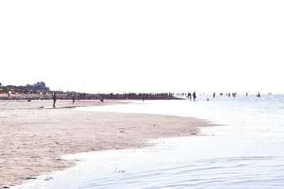 Group of people on beach against clear sky