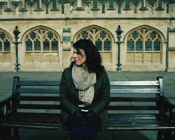 Woman sitting on bench against church