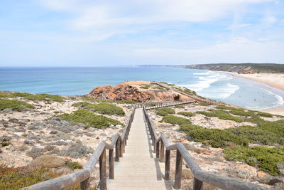 Boardwalk leading towards sea against sky