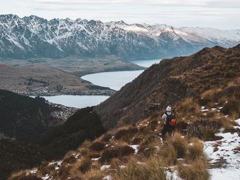 Rear view woman standing on snowcapped mountains during winter